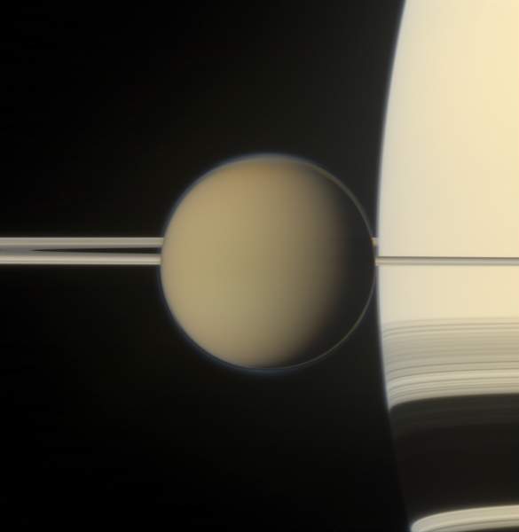 Il tenebroso satellite Titano in primo piano davanti a Saturno e ai suoi anelli